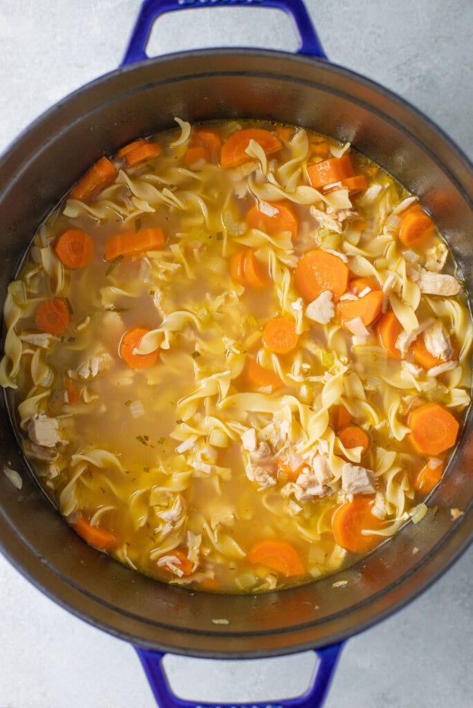 A large pot of turkey noodle soup on a gray background