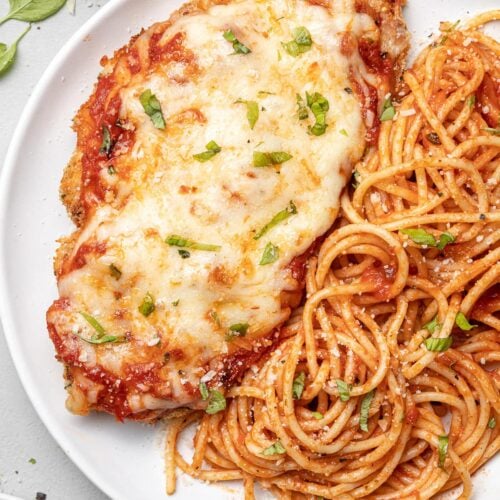 A plate of baked chicken parmesan with pasta