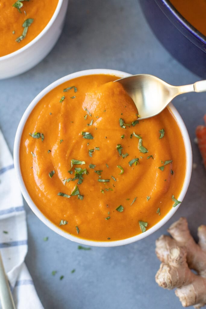 A bowl of carrot ginger soup with a spoonful being taken out of it