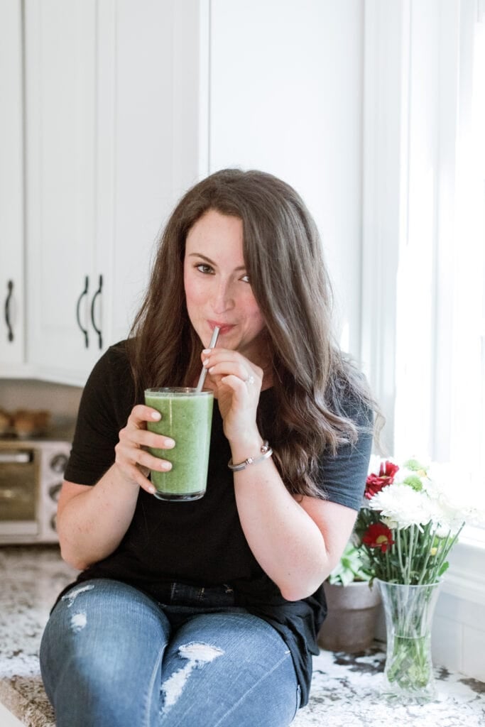 A girl drinking a green SmoothieBox Smoothie