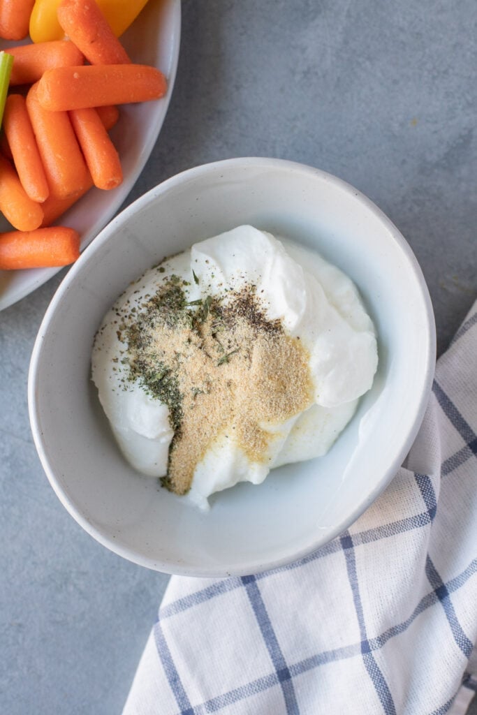 All ingredients for yogurt veggie dip in a white bowl before mixing