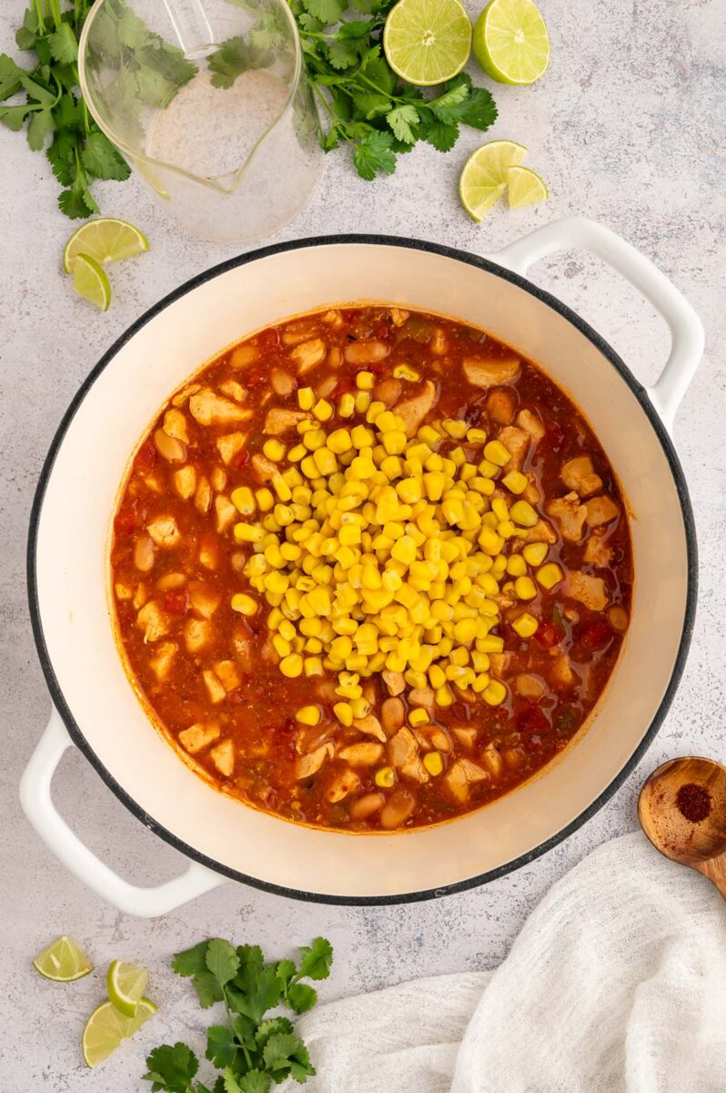White Bean Chicken Chili in a dutch oven with corn on top that hasn't been stirred in yet.