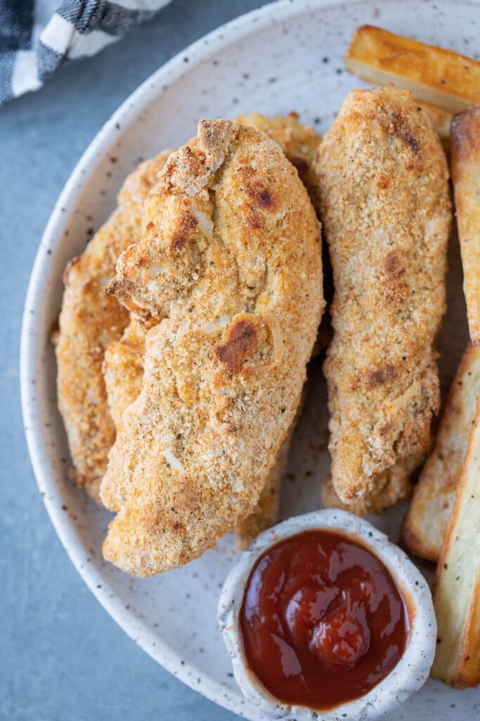 Healthy Chicken Tenders on a white plate with a grey background