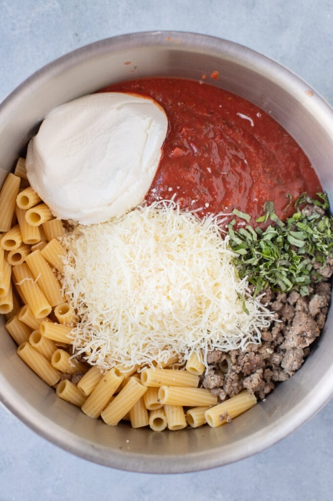 Cooked ziti in a large pot with ricotta, ground turkey, tomato sauce, shredded mozzarella and parmesan cheeses and chopped fresh basil.