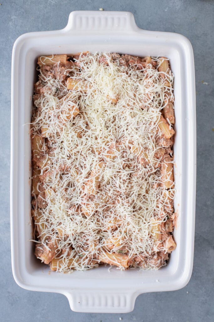 Unbaked casserole topped with shredded white cheese, viewed from overhead.