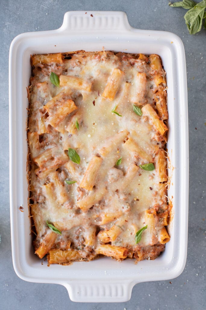 Cheesy baked ziti with ricotta in a white casserole dish, viewed from above.