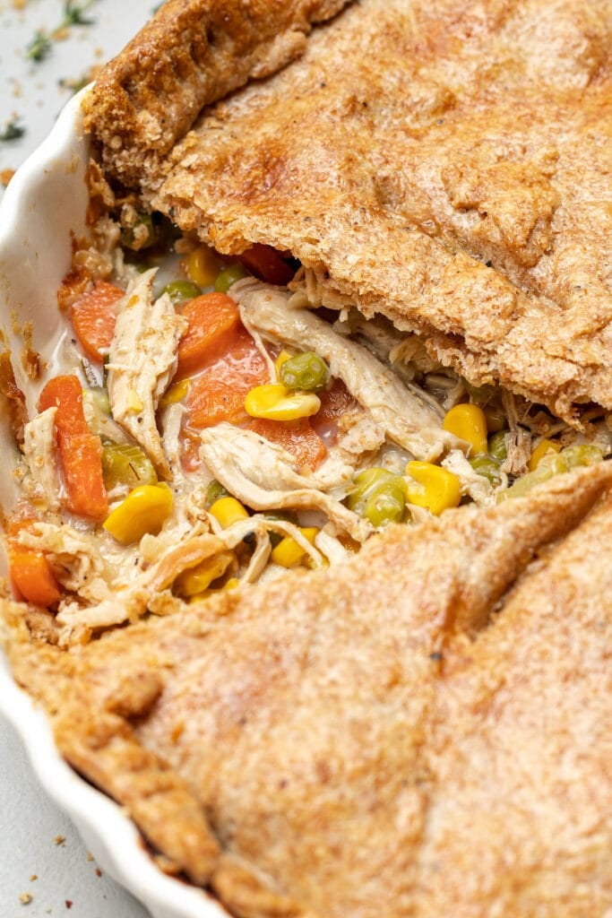 A side view of healthy Chicken Pot Pie with a piece taken out of it on a grey background