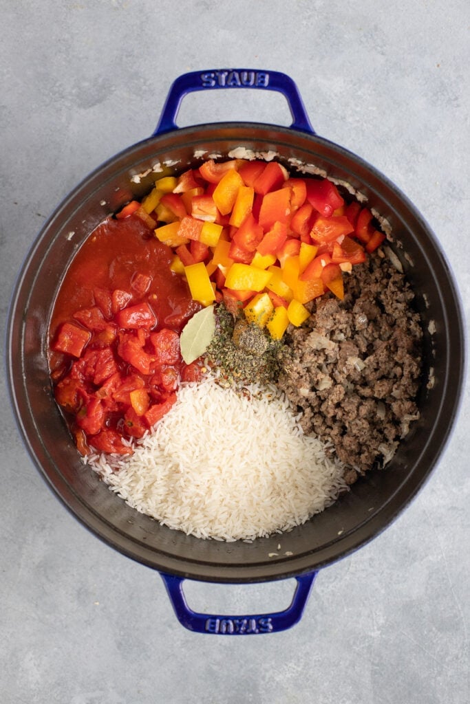 All ingredients for stuffed pepper soup in a stock pot unmixed and uncooked