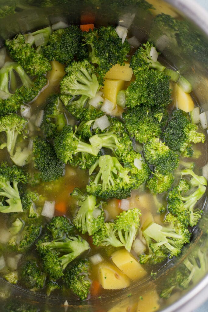 A close up of broccoli soup in a pot before it cooks