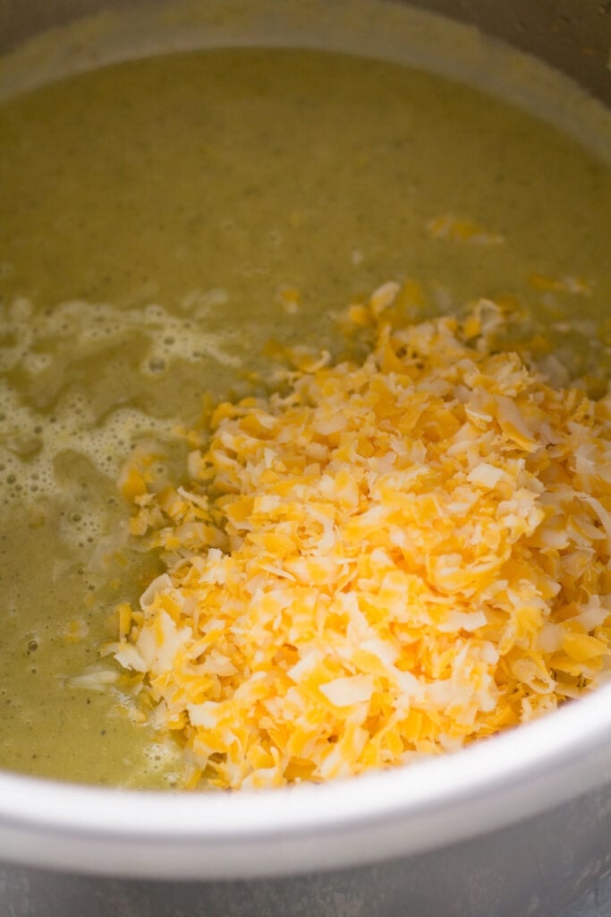 healthy broccoli soup with cheddar cheese being added