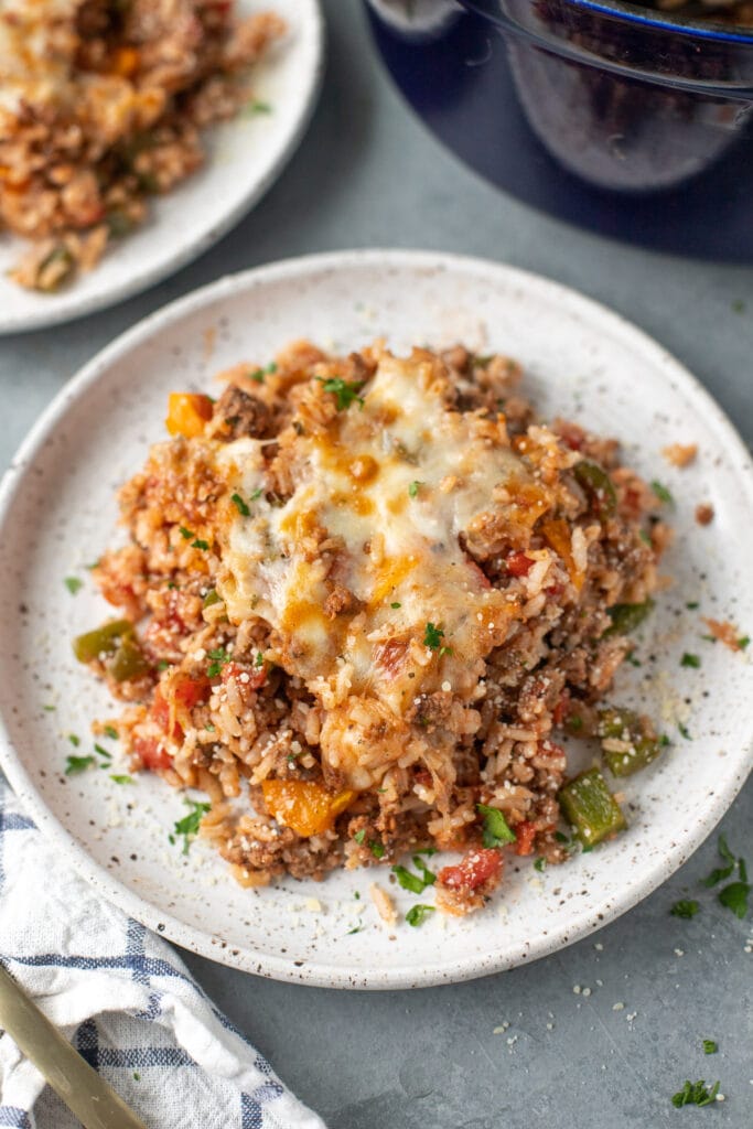 a plate of stuffed bell pepper casserole with another plate on the side on a grey background