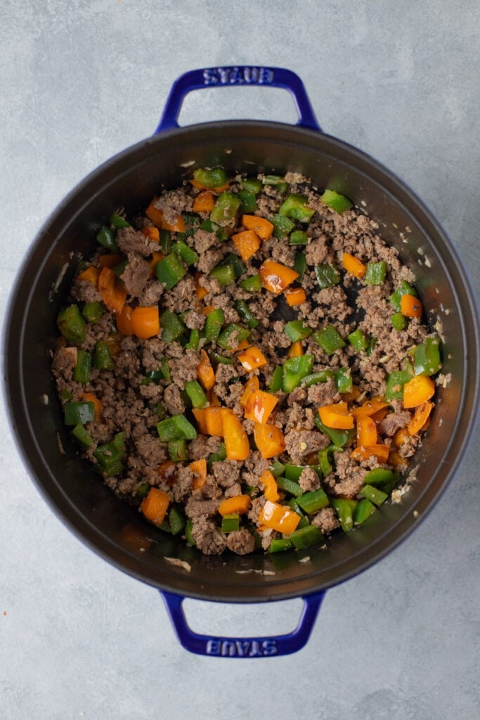 Dutch oven with sautéd garlic, onion, peppers and beef for stuffed pepper casserole