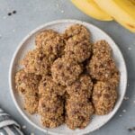 An overhead shot of healthy banana breakfast cookies on a white plate with a grey background
