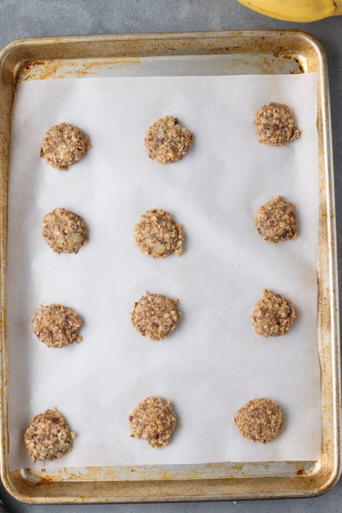 healthy banana cookies (uncooked) on a parchment lined cookie sheet