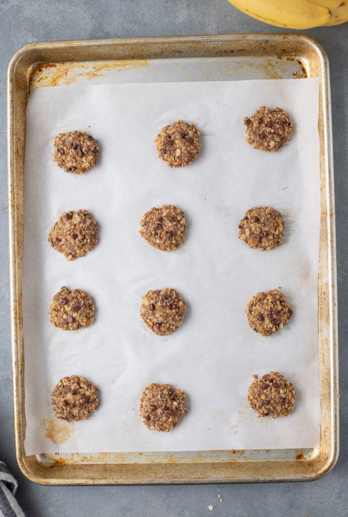 healthy banana cookies on a parchment lined cookie sheet fully cooked
