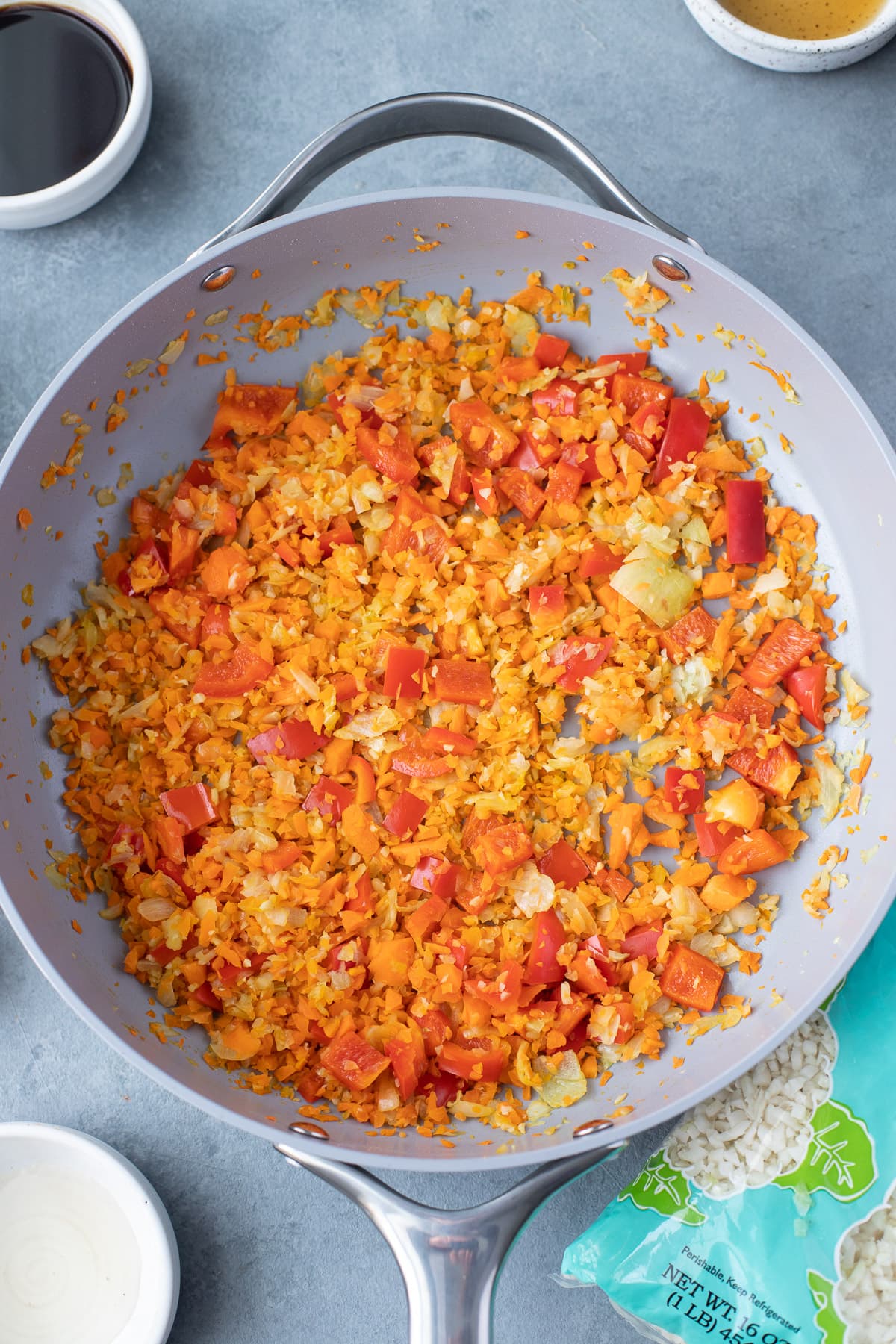 Sautéd olive oil, onions, garlic, peppers, and carrots in a pan for cauliflower fried rice