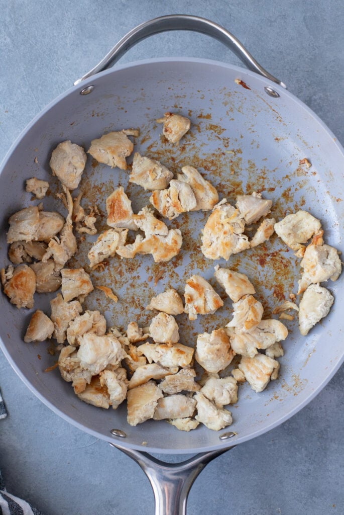 Browned chicken in a pan for chicken paella
