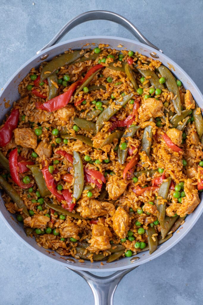 A pan of chicken paella on a grey background