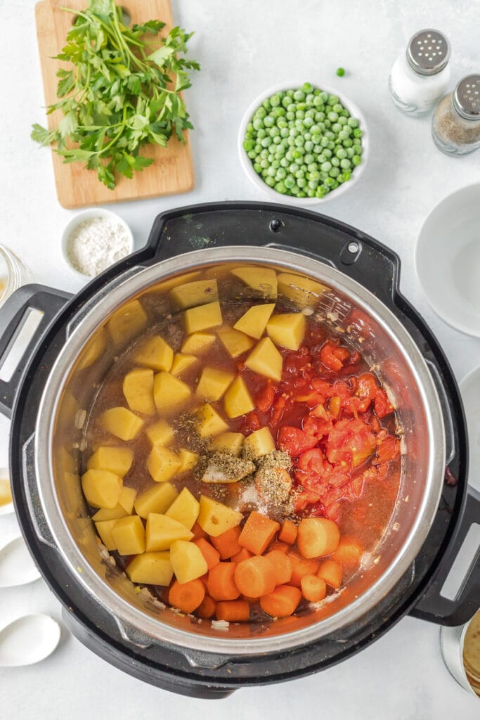 Hamburger Stew before being cooked. An overhead view into an instant pot with beef, potatoes, carrots and tomatoes