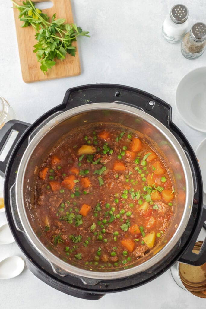 Peas being stirred into ground beef stew in an instant pot