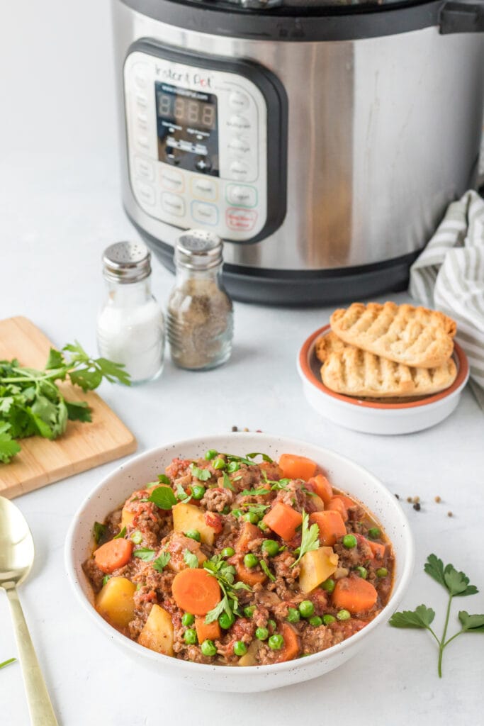 A bowl og round beef stew with the instant pot in the background