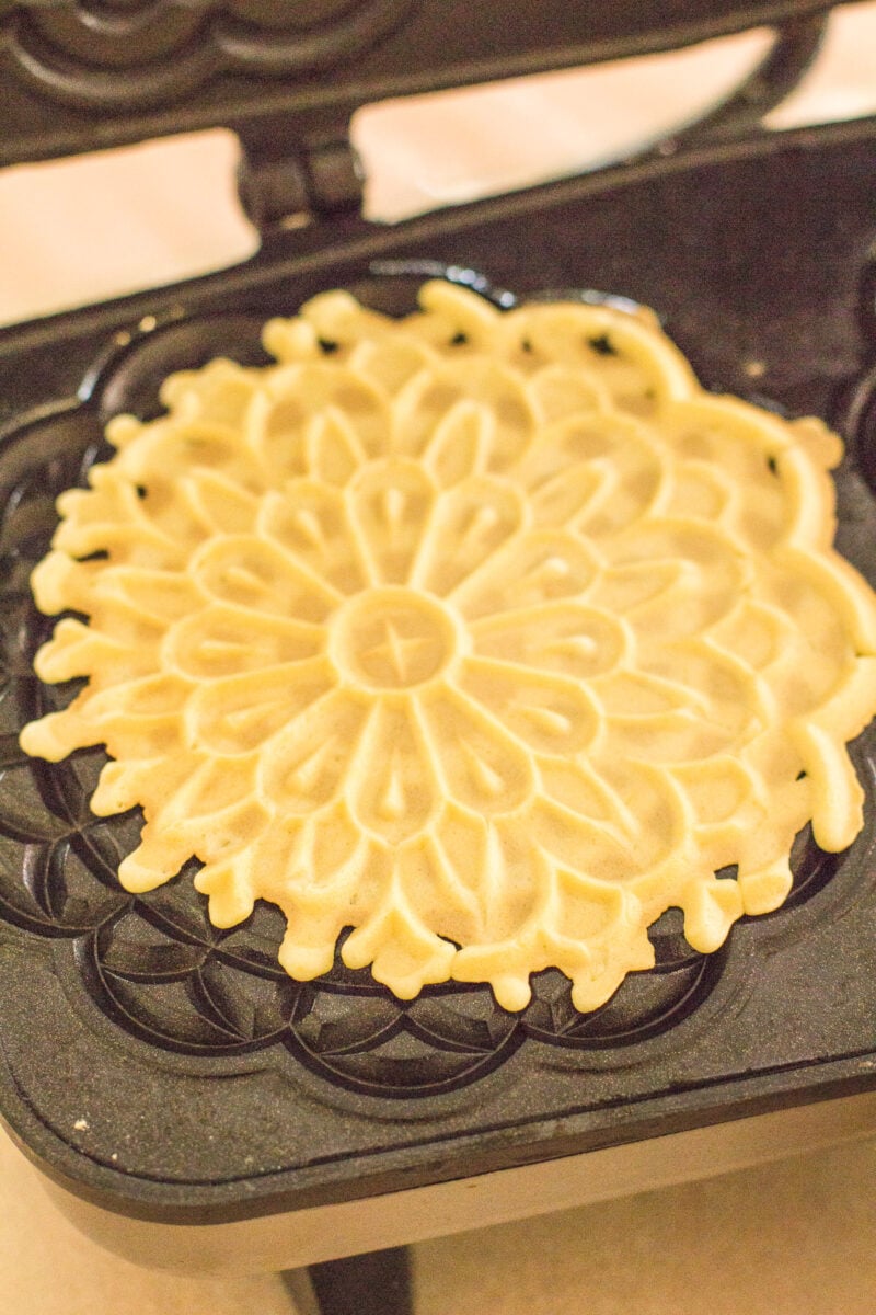 A pizzelle being lifted from a press.