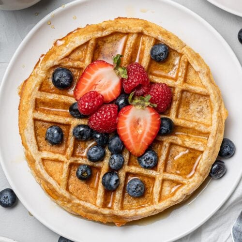 an overhead shot of healthy protein waffles with strawberries and blueberries on top