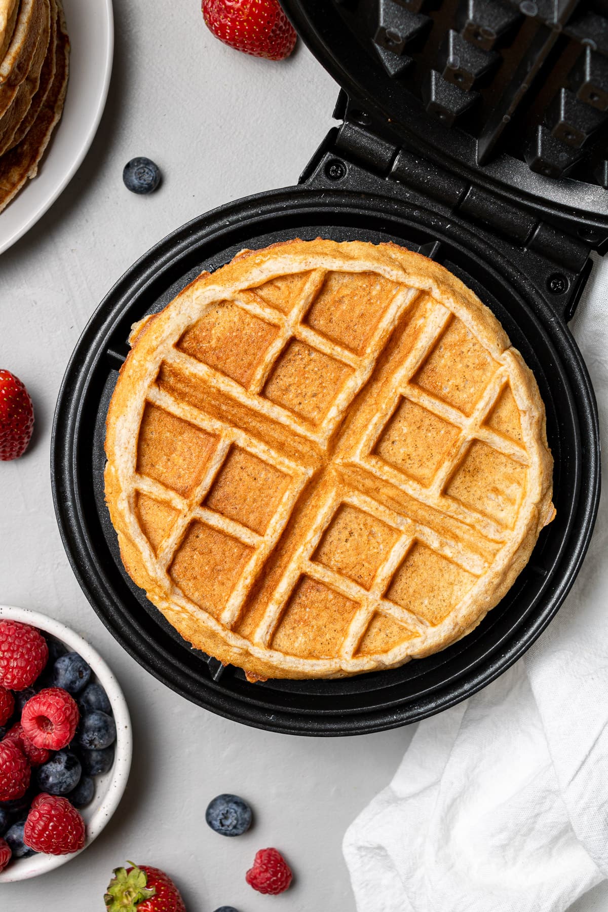 a cooked healthy protein waffle in the waffle iron on a grey background