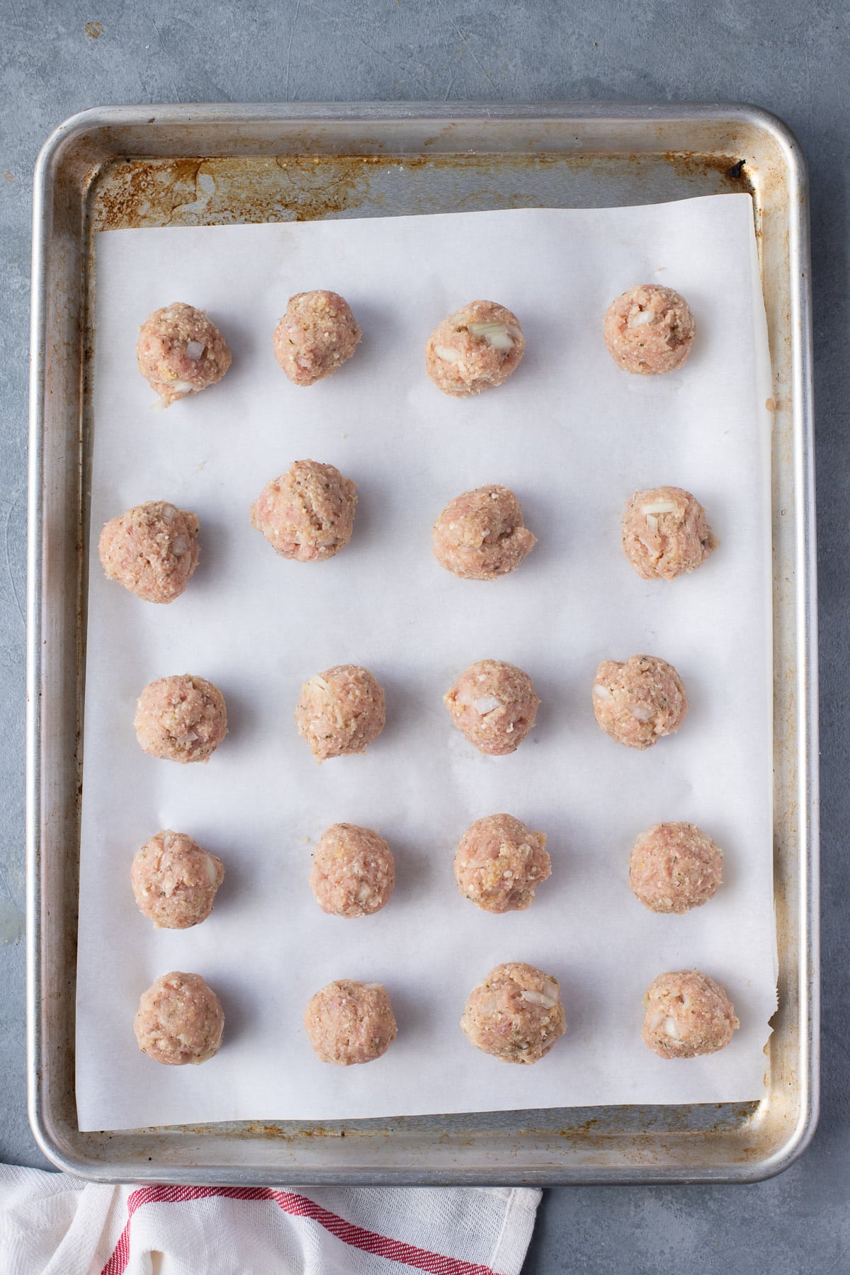 uncooked ground turkey meatballs on a parchment lined sheet pan, viewed from overhead.
