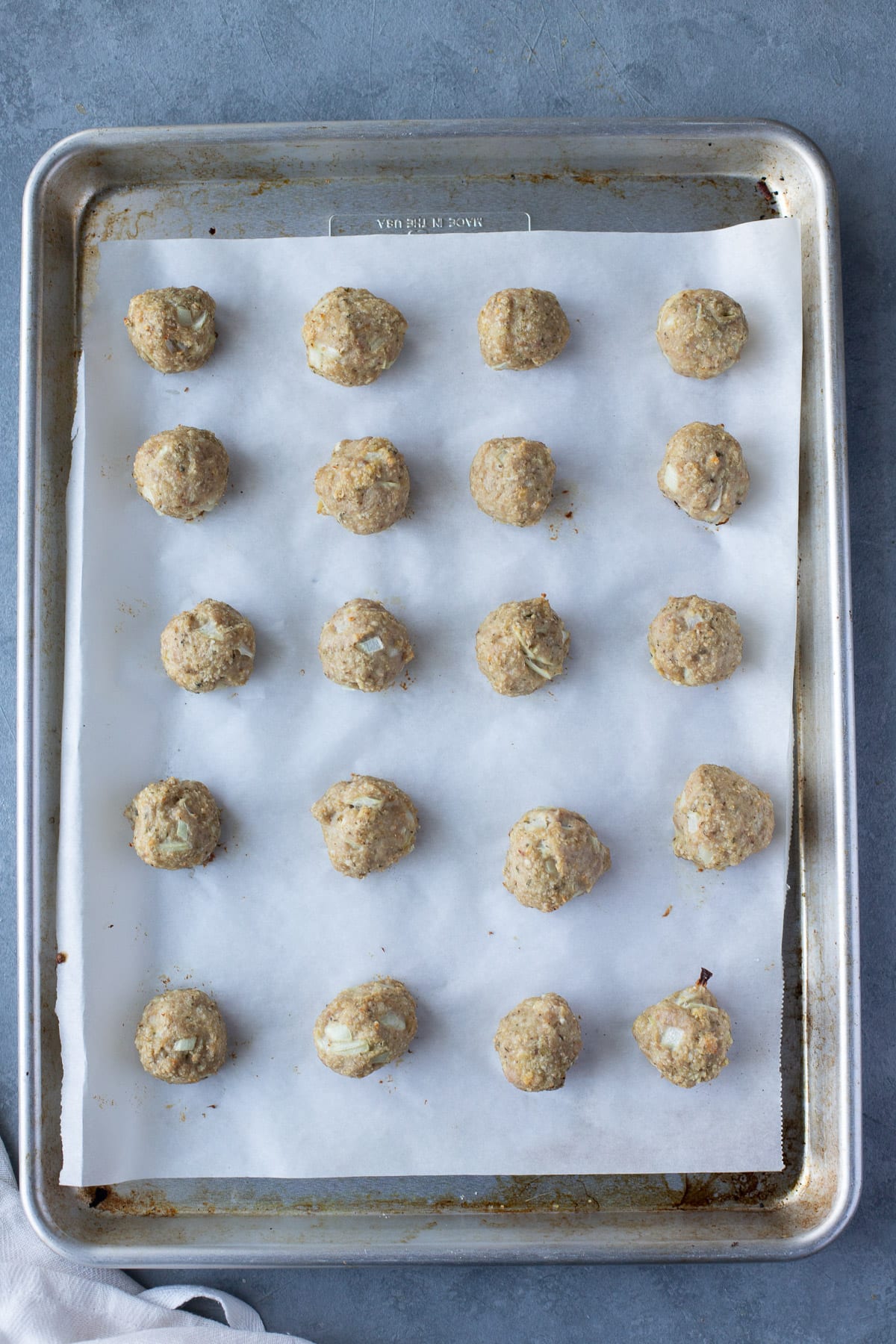 Baked Italian turkey meatballs on a parchment lined sheet pan, viewed from overhead.