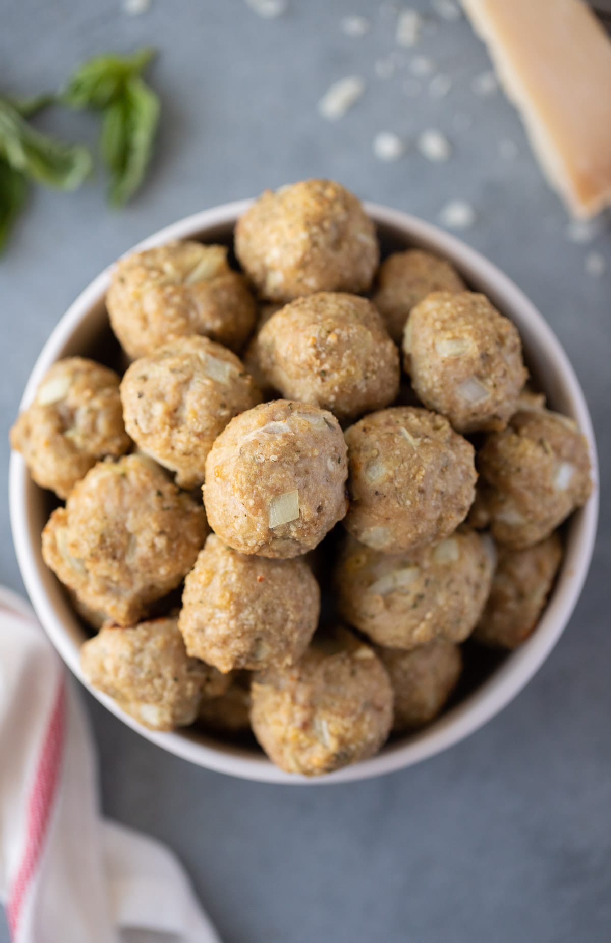 Overhead view of ground turkey meatballs stacked in a white bowl.