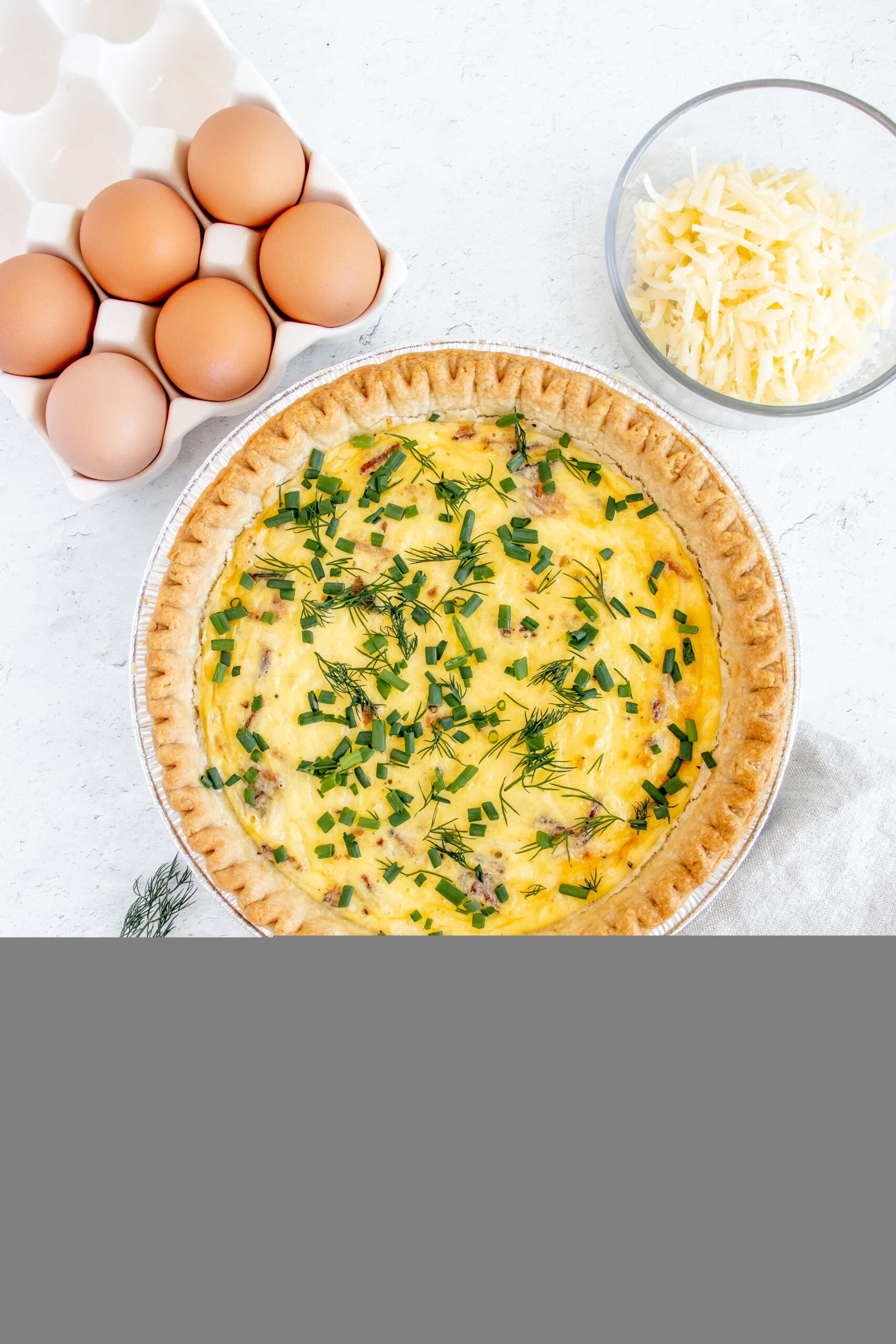 bacon and cheese quiche with fresh herbs on top with eggs and cheese on the side