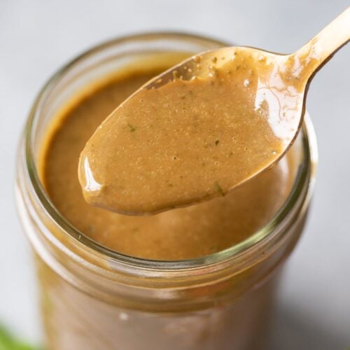 Creamy balsamic dressing in a mason jar with a spoon taking a little out of it