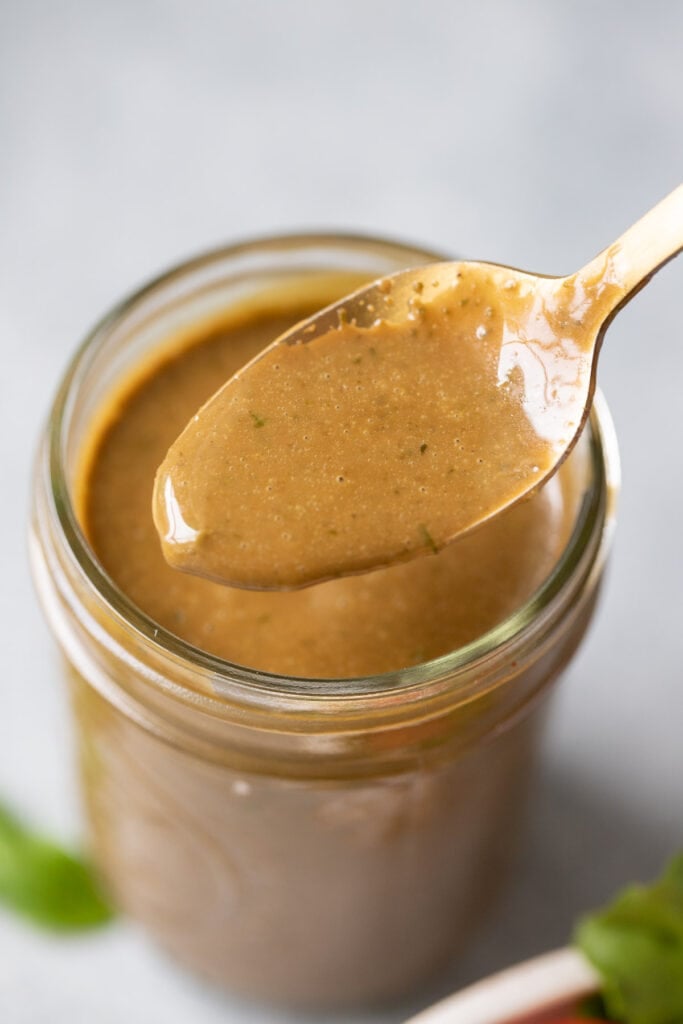 Creamy balsamic dressing in a mason jar with a spoon taking a little out of it