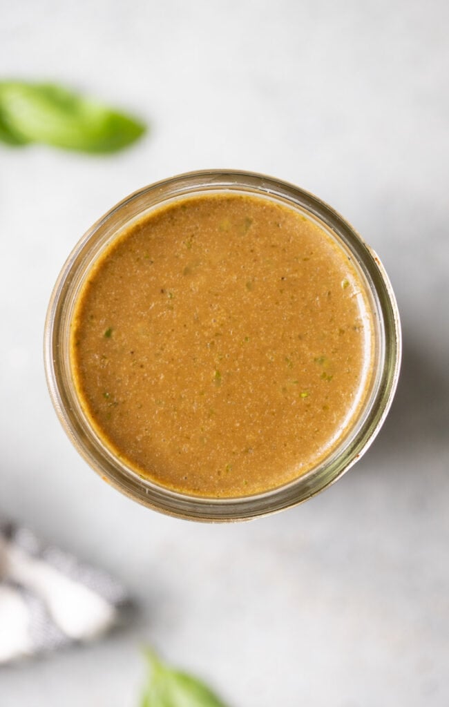 an overhead shot of creamy balsamic dressing in a mason jar on a grey background