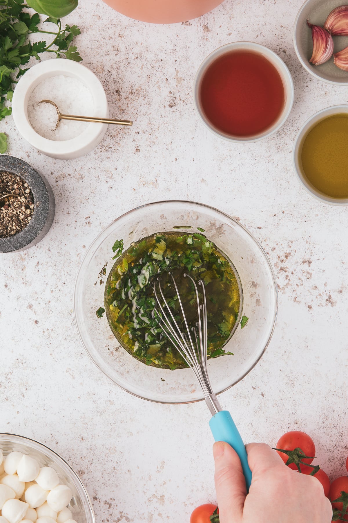 A bowl of dressing for caprese pasta salad being whisked together