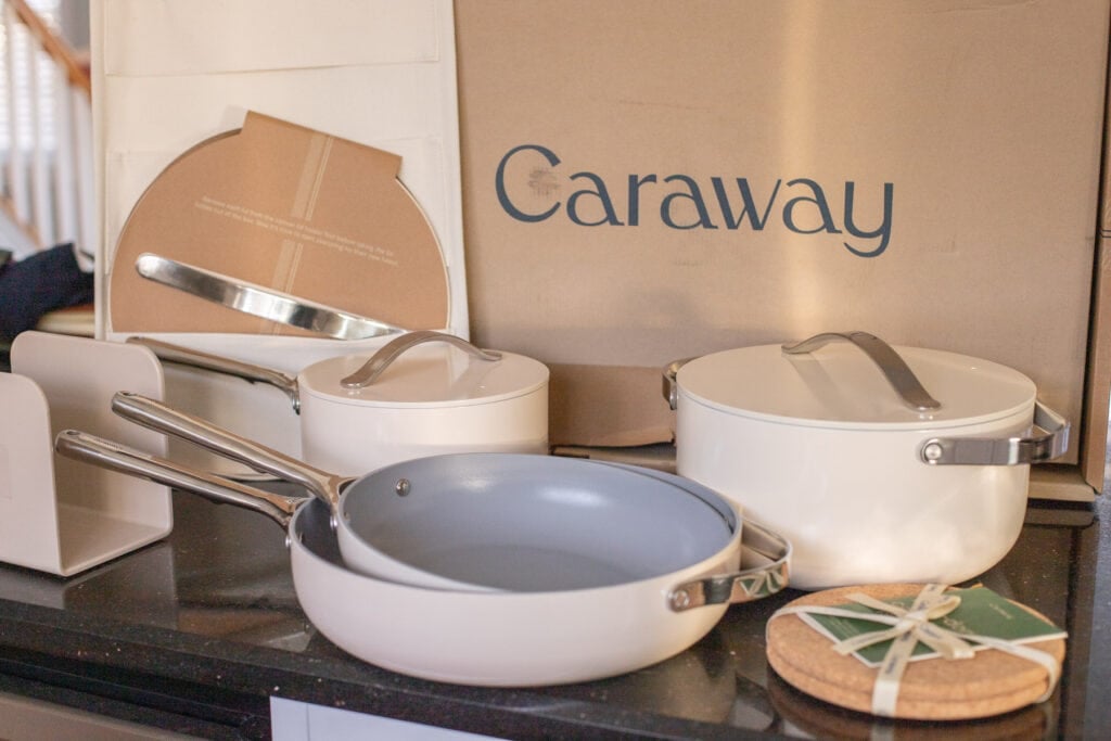A close up of Caraway Cookware unboxed on a black kitchen counter