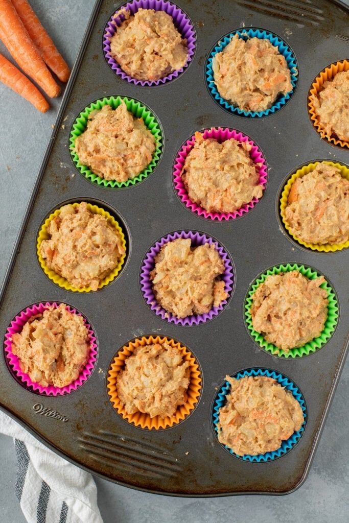 healthy carrot muffin batter in muffin liners in a metal muffin pan uncooked