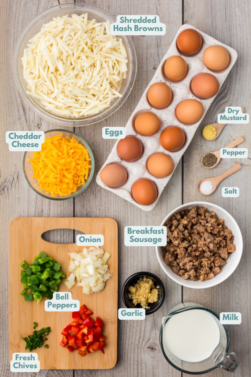 Ingredients for crock pot breakfast casserole in bowls: frozen shredded hash browns, salt, pepper, breakfast sausage, cheddar cheese, yellow onion, bell peppers, large eggs, milk, garlic, dry mustard, chives