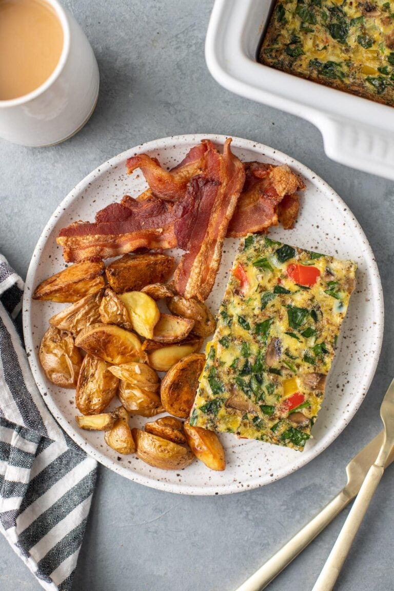 an overhead shot of healthy breakfast casserole on a white plate with bacon and crispy potatoes