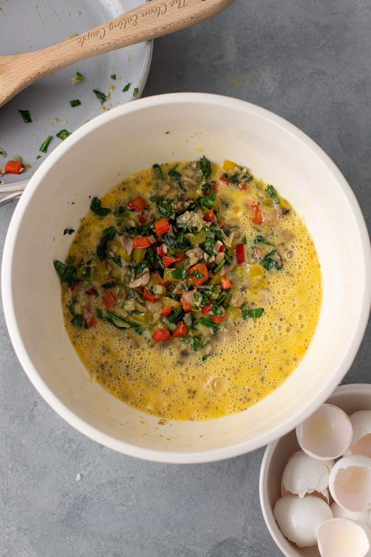 A bowl of eggs, cheese and sauteed veggies before being mixed for healthy breakfast casserole