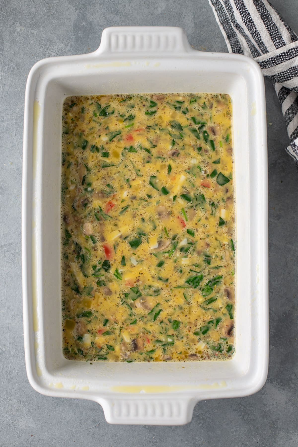 healthy egg bake in a white baking dish before being baked