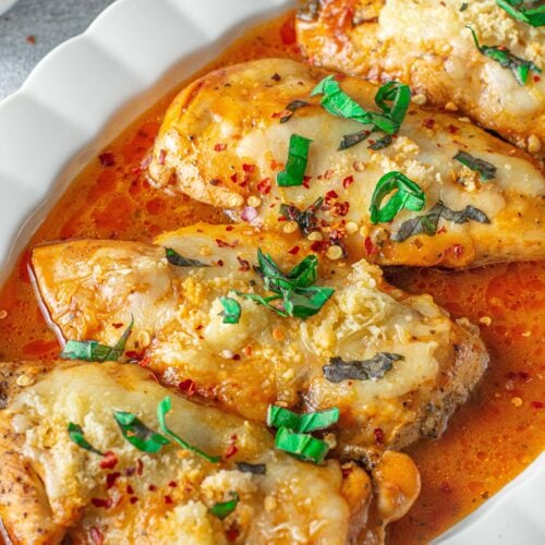 a white platter with instant pot chicken parmesan on top with herbs on top