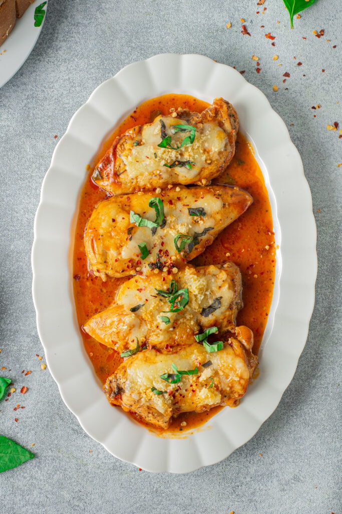 An overhead shot of instant pot chicken parmesan on a white platter with a grey background