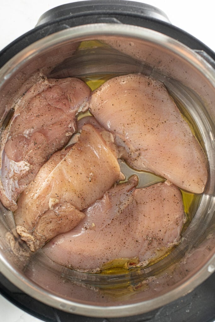 uncooked chicken breasts in an instant pot with olive oil for keto chicken parmesan