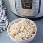 Easy Instant Pot Shredded Chicken in a blue bowl with a pressure cooker behind it