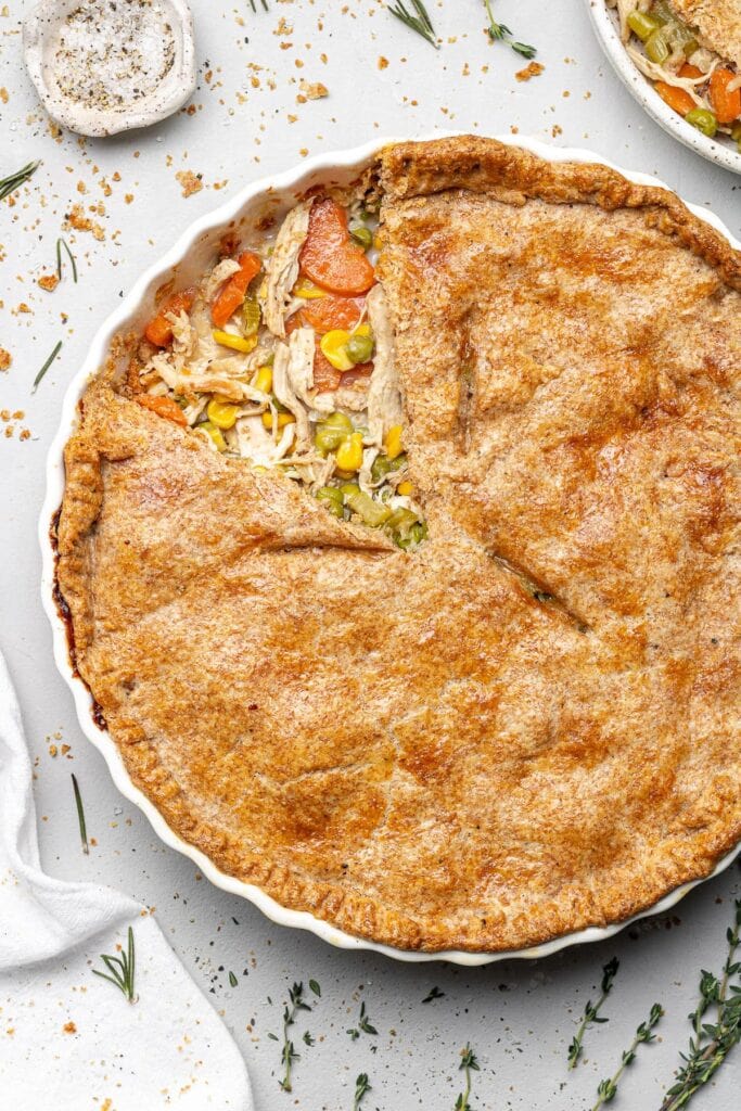 An overhead shot of healthy Chicken Pot Pie made with instant pot shredded chicken with a piece taken out of it on a grey background