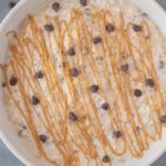 A close up of peanut butter overnight oats with chocolate chips and peanut butter drizzle on top