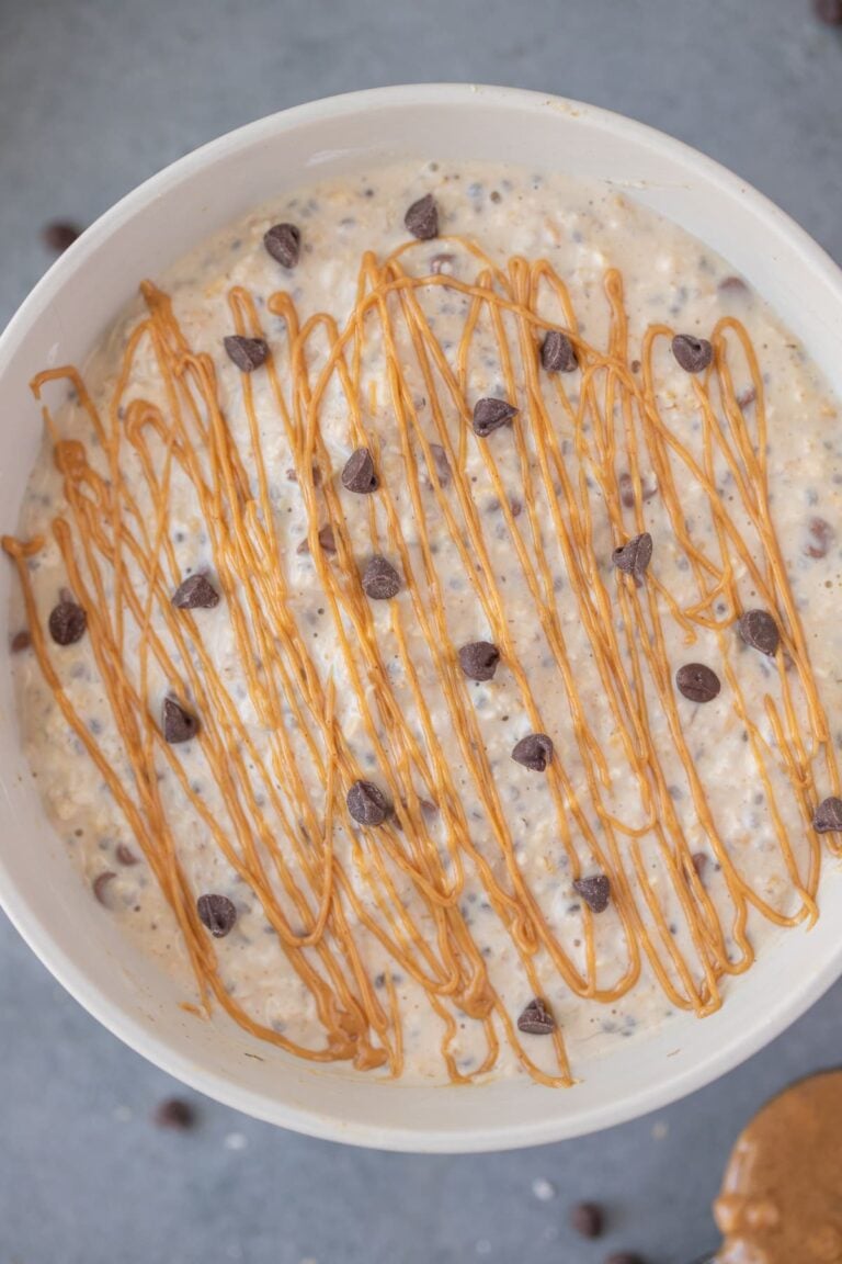 A close up of peanut butter overnight oats with chocolate chips and peanut butter drizzle on top
