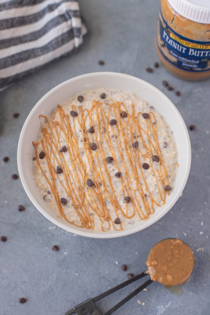 peanut butter overnight oats with chocolate chips and peanut butter drizzle on top with peanut butter on the side